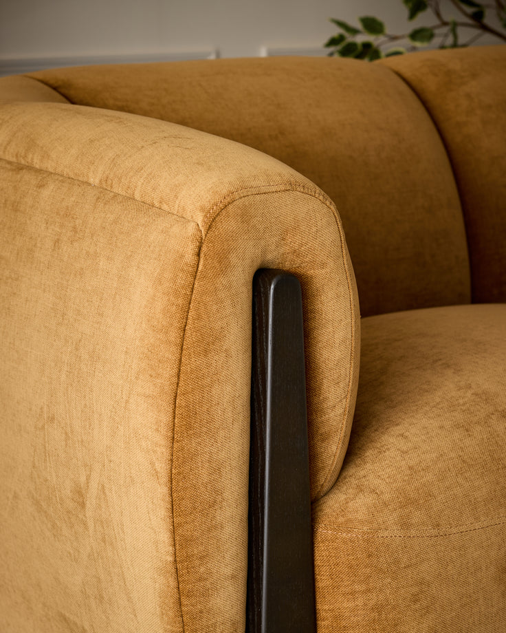 Teagan 2-seater sofa in ochre fabric with dark wooden armrest detail, angled close-up view.