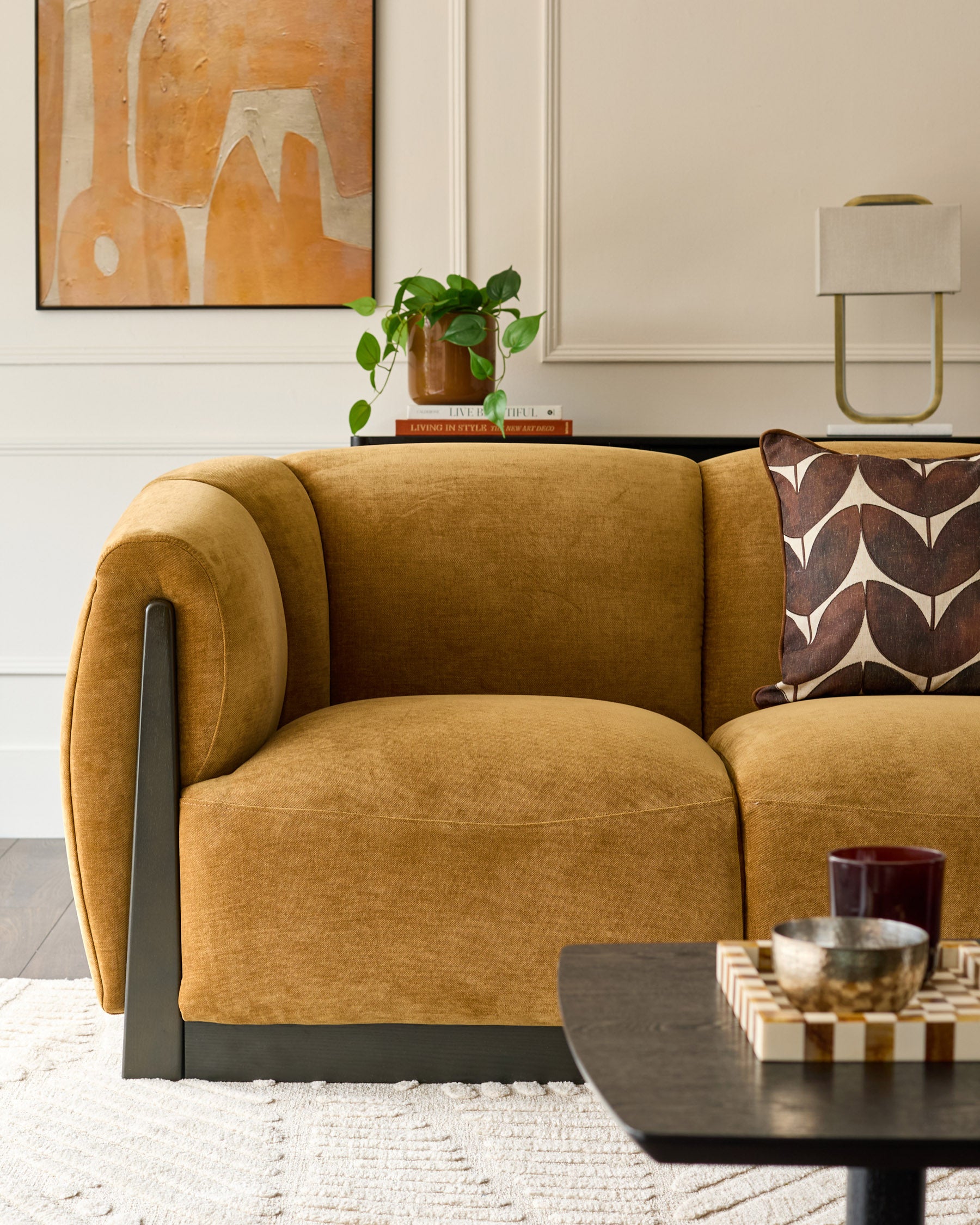 Teagan 3-seater sofa in ochre fabric with curved arms and dark metal legs, styled in a modern living room setting.