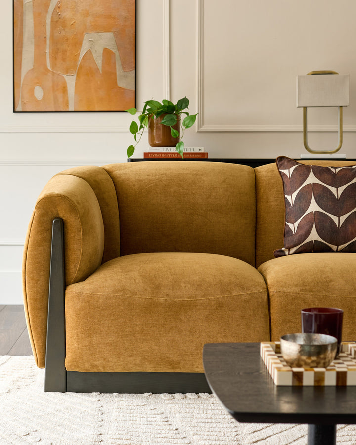 Teagan 3-seater sofa in ochre fabric with curved arms and dark metal legs, styled in a modern living room setting.