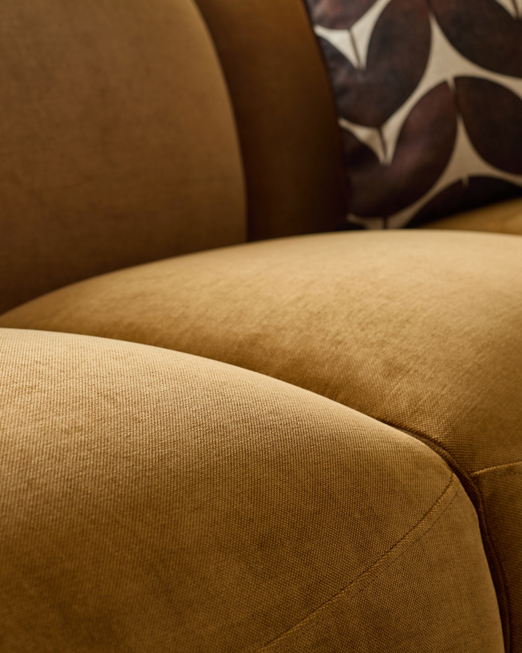 Close-up of Teagan 3-seater sofa in ochre fabric, showing textured weave and curved armrest detail.