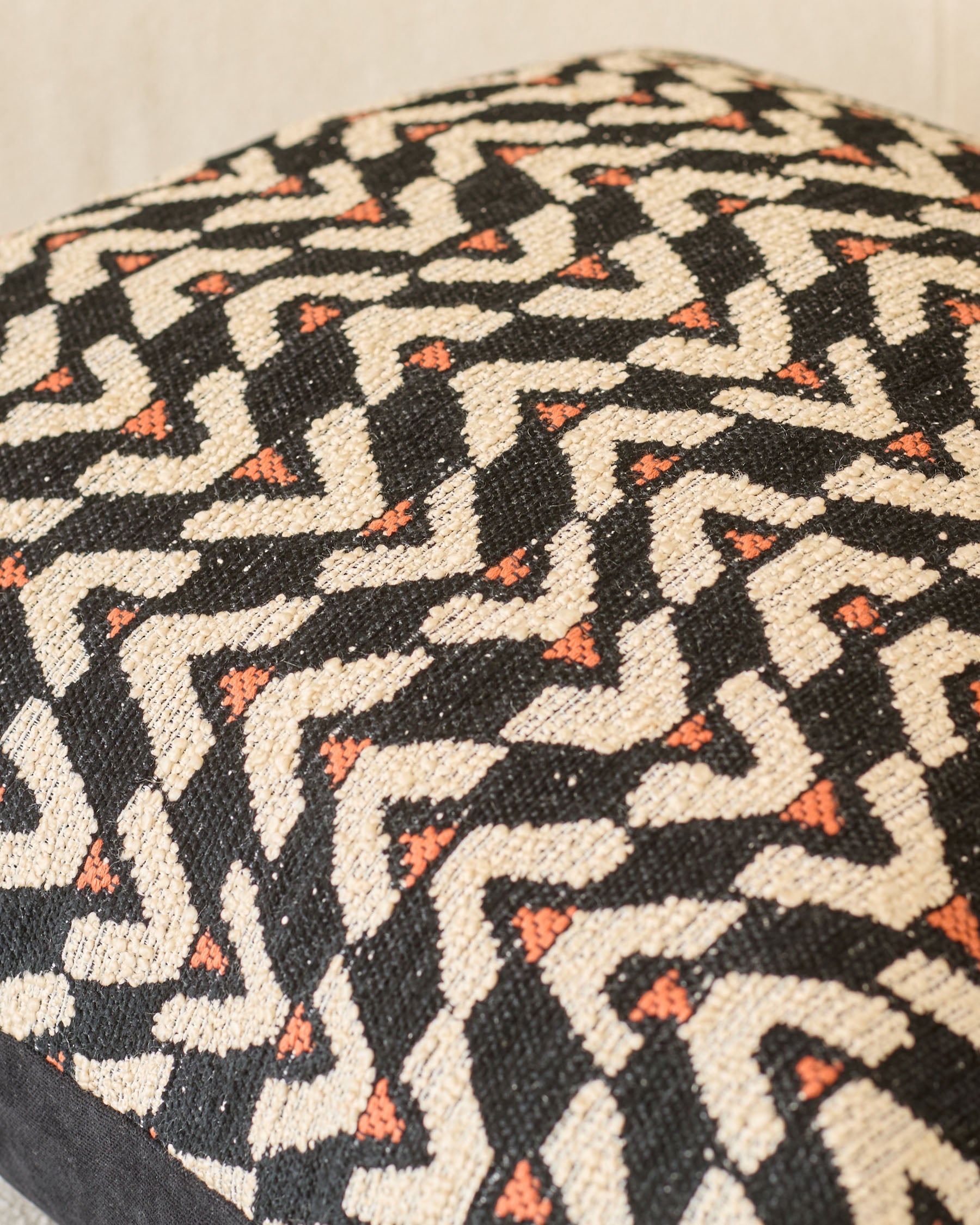 Teela cushion in black with cream and orange geometric patterned weave, close-up detail view.