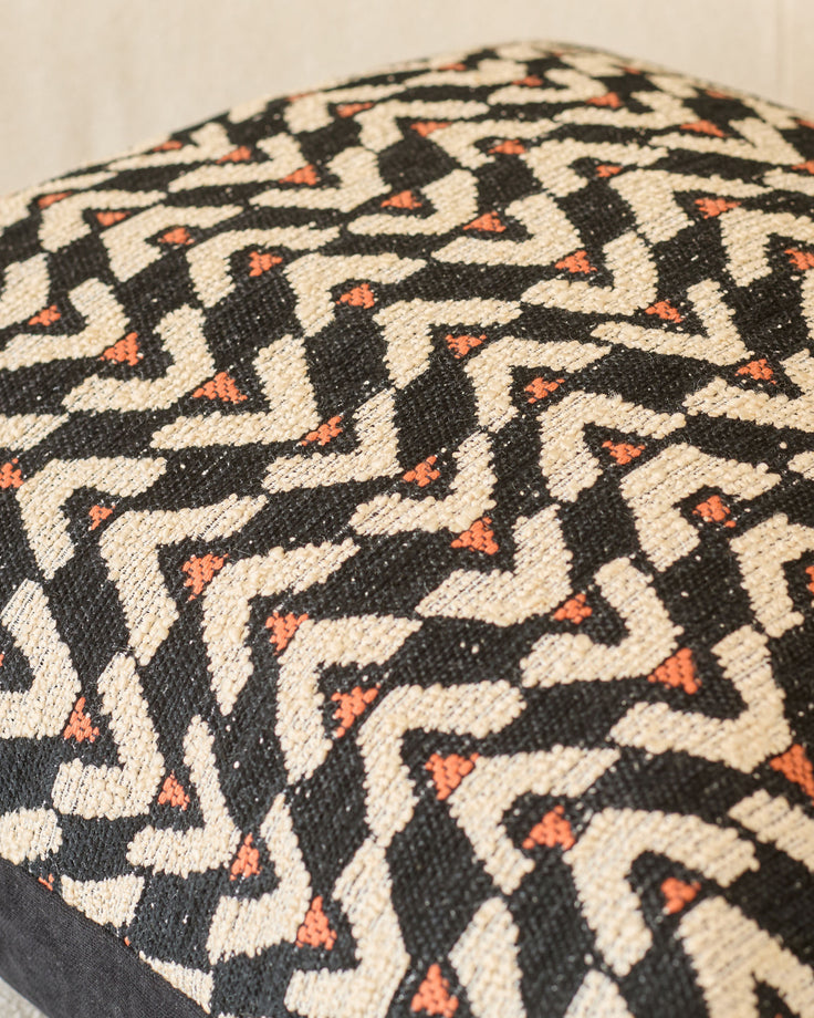 Teela cushion in black with cream and orange geometric patterned weave, close-up detail view.