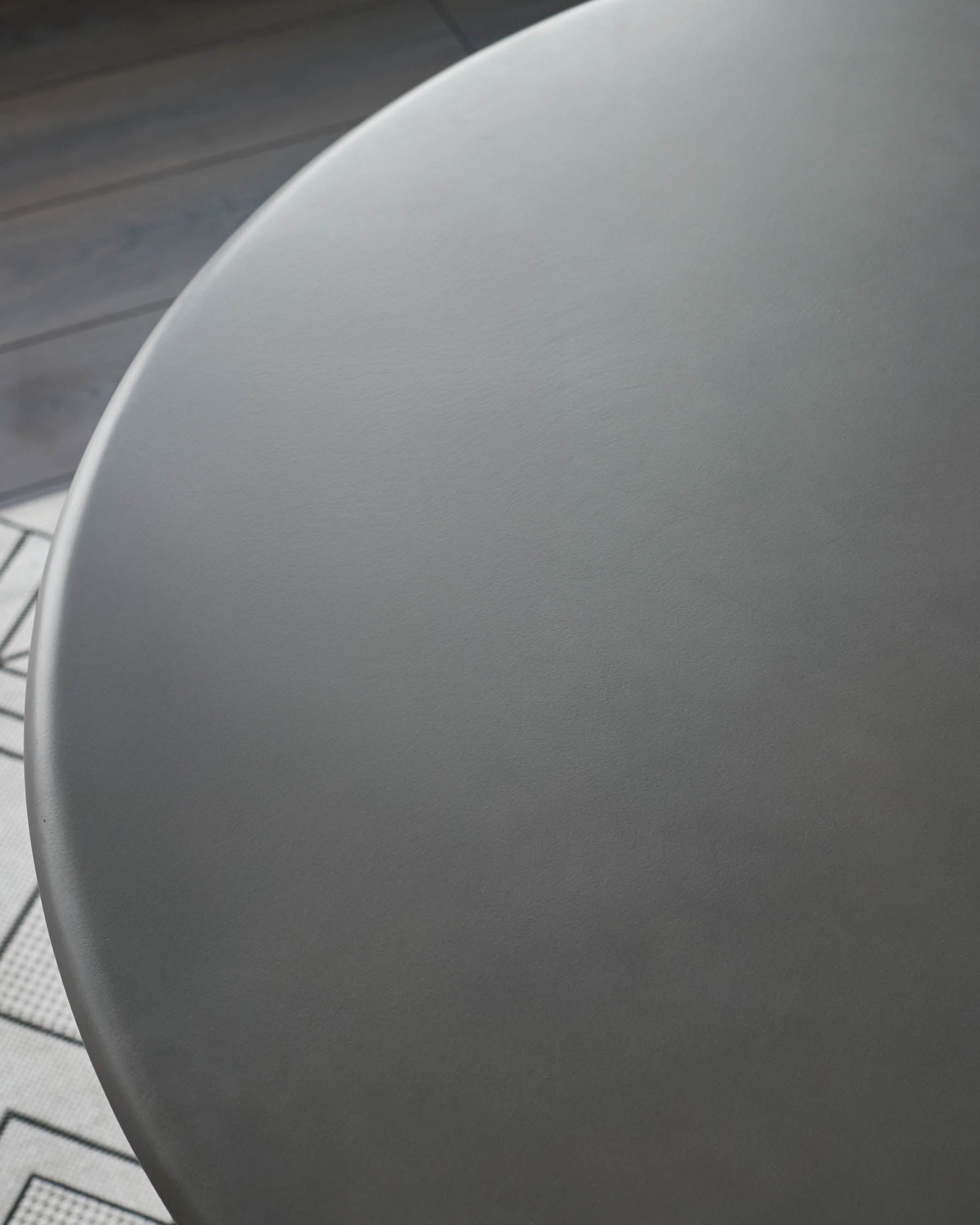 Close-up of round white dining table top surface with smooth finish and curved edge detail.