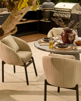 Tesso round dining table with Camilo chairs in natural and dark grey, outdoor patio setting with place settings and decor.