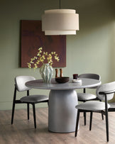 Tesso Garden dark grey round dining table with pedestal base, seated with four chairs in a modern dining room setting.