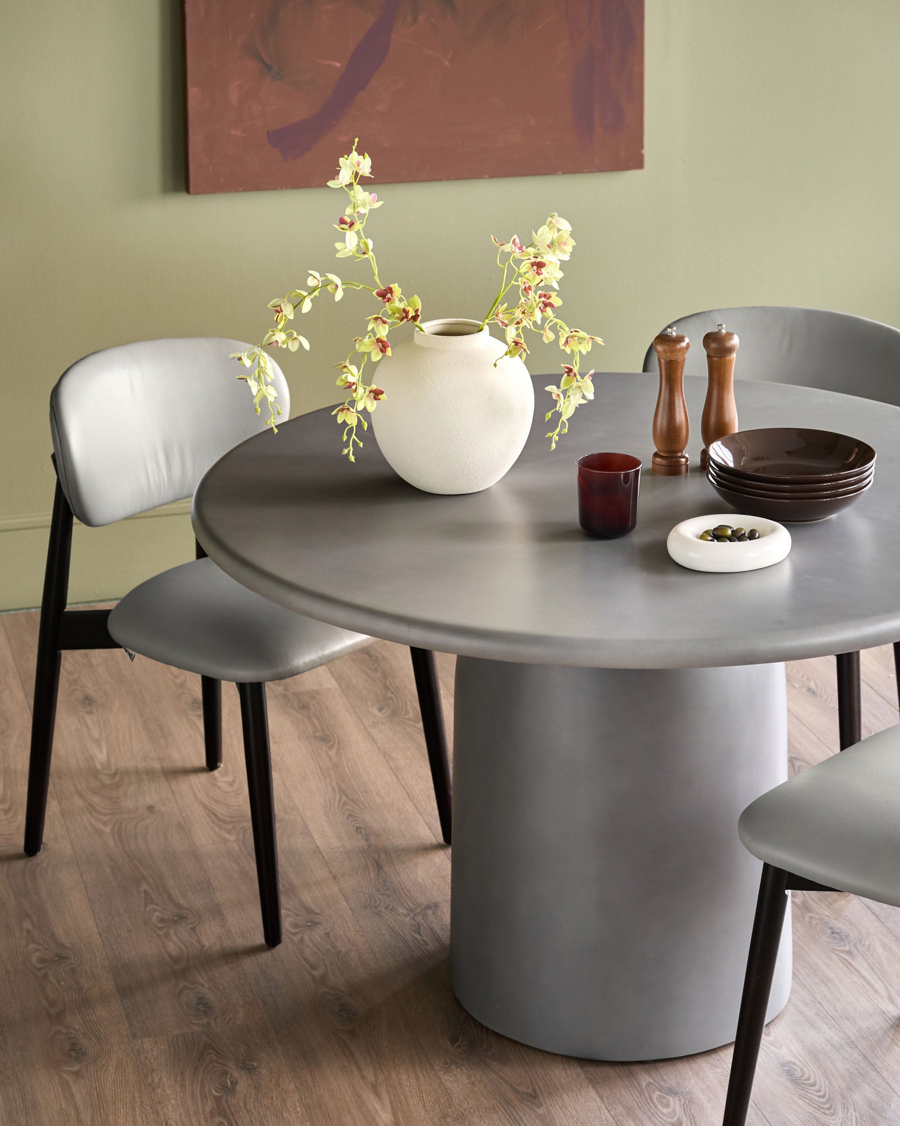 Tesso Garden dark grey round dining table styled with chairs, tableware, and white vase with flowers.