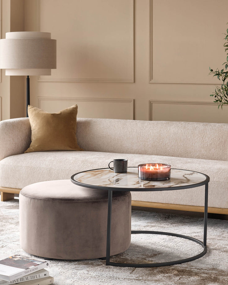 Thea black round coffee table with marble top and matching mocha pouffe in modern living room setting.