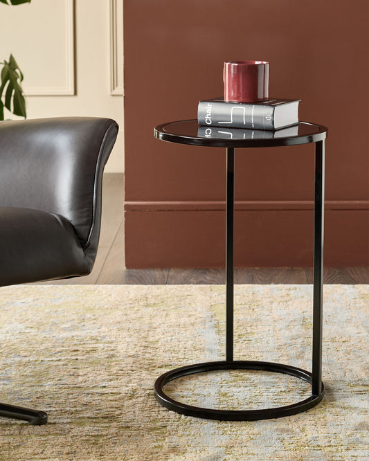 Thea smoked mirror tray table in black with round top and curved base, styled in living room setting.