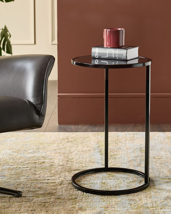Thea smoked mirror tray table in black with round top and curved base, styled in living room setting.