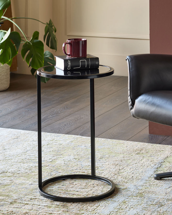 Thea smoked mirror tray table in black with round top and base, styled in a modern living room setting.