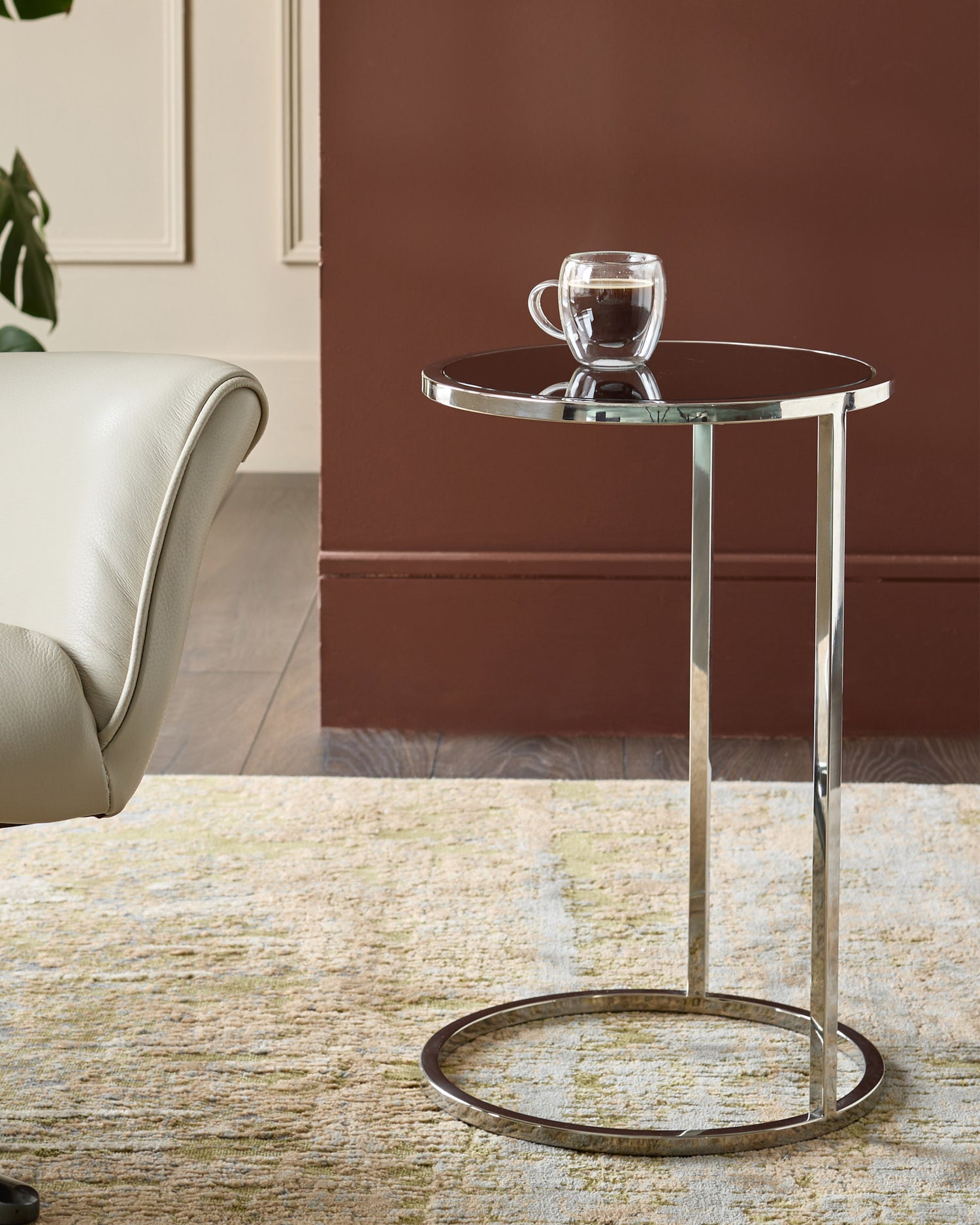 Thea smoked mirror tray table with polished stainless steel frame and base, displayed in a modern living room setting.