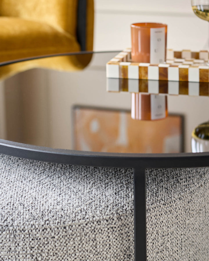 Black round coffee table with grey textured surface and matching grey pouffe, styled with home décor accessories.