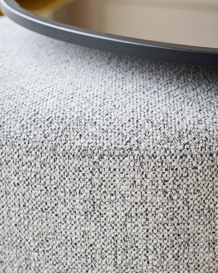 Close-up of grey textured fabric surface with black round table edge visible at top
