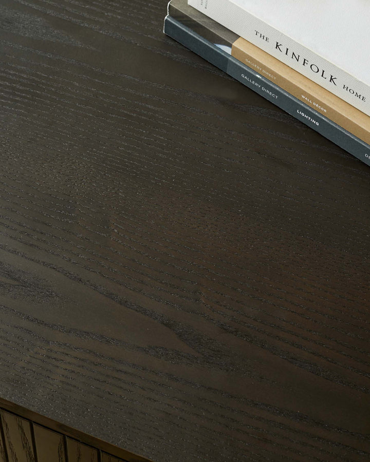 Close up of a dark wood table with books on top, featuring a subtle grain pattern.