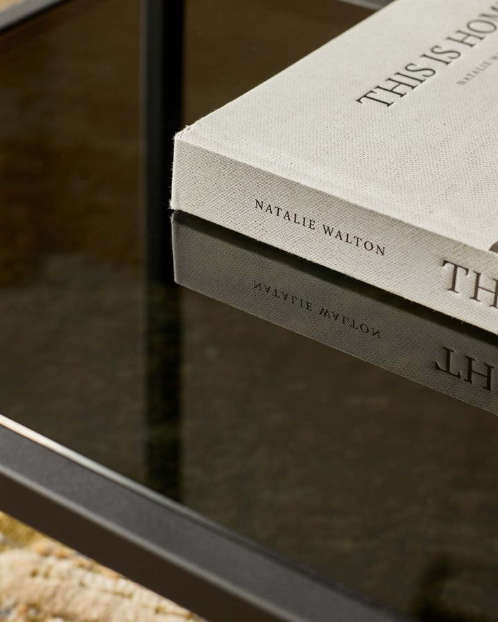A sleek side table with a tinted glass top and a contemporary black frame, ideal for modern living spaces.