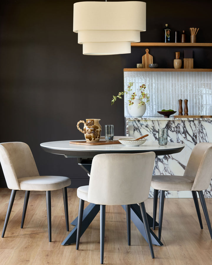 Champagne velvet dining chair with curved back and black tapered legs, shown in a modern dining room setting.