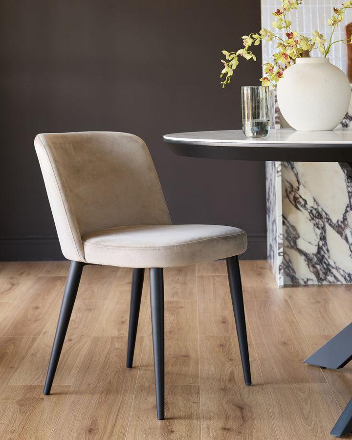 Trinny velvet dining chair in champagne with black tapered legs, shown in a styled interior setting.