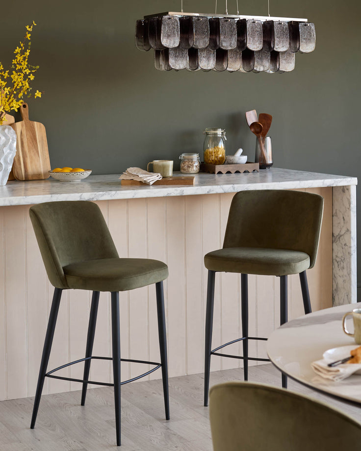 Stylish kitchen featuring two olive-green bar stools with black legs, plus a round dining table with matching stools.