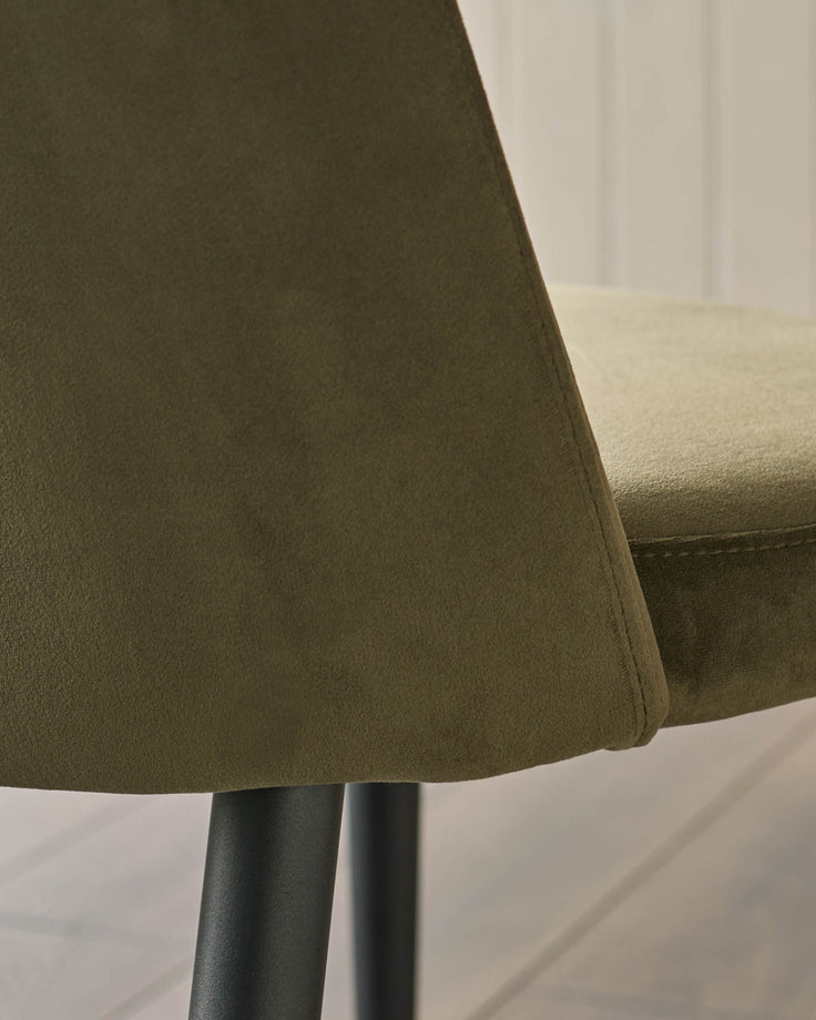 Close-up of an olive-green chair with black metal legs, showcasing its textured fabric and modern design.
