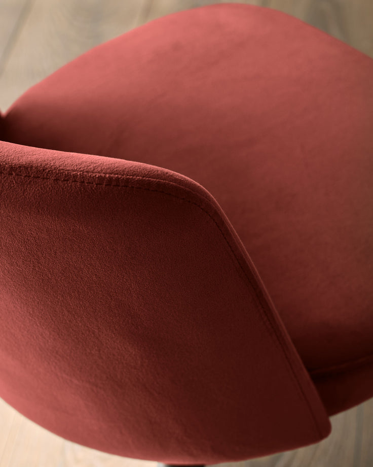 Close-up of a stylish, comfy-looking chair in a deep, rich red velour. Perfect for adding a touch of sophistication to any room.