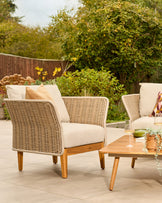 Tuscany garden set with woven rattan armchair, cream cushions, wooden legs, and wooden coffee table on patio.