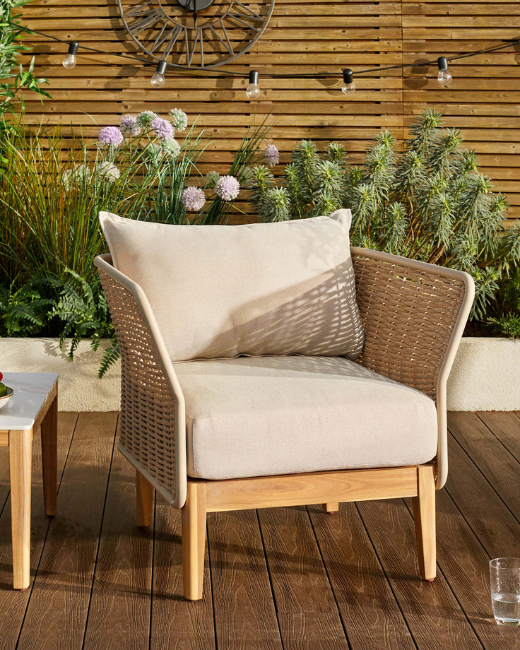 Tuscany garden armchair in natural acacia wood with woven rattan sides and cream cushions, positioned on a wooden deck.