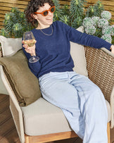 Tuscany garden armchair in natural acacia wood and cream fabric, shown in outdoor setting with person seated.