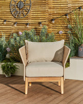 Tuscany garden armchair in natural acacia wood with cream fabric cushions, woven rattan armrests, displayed on wooden deck.