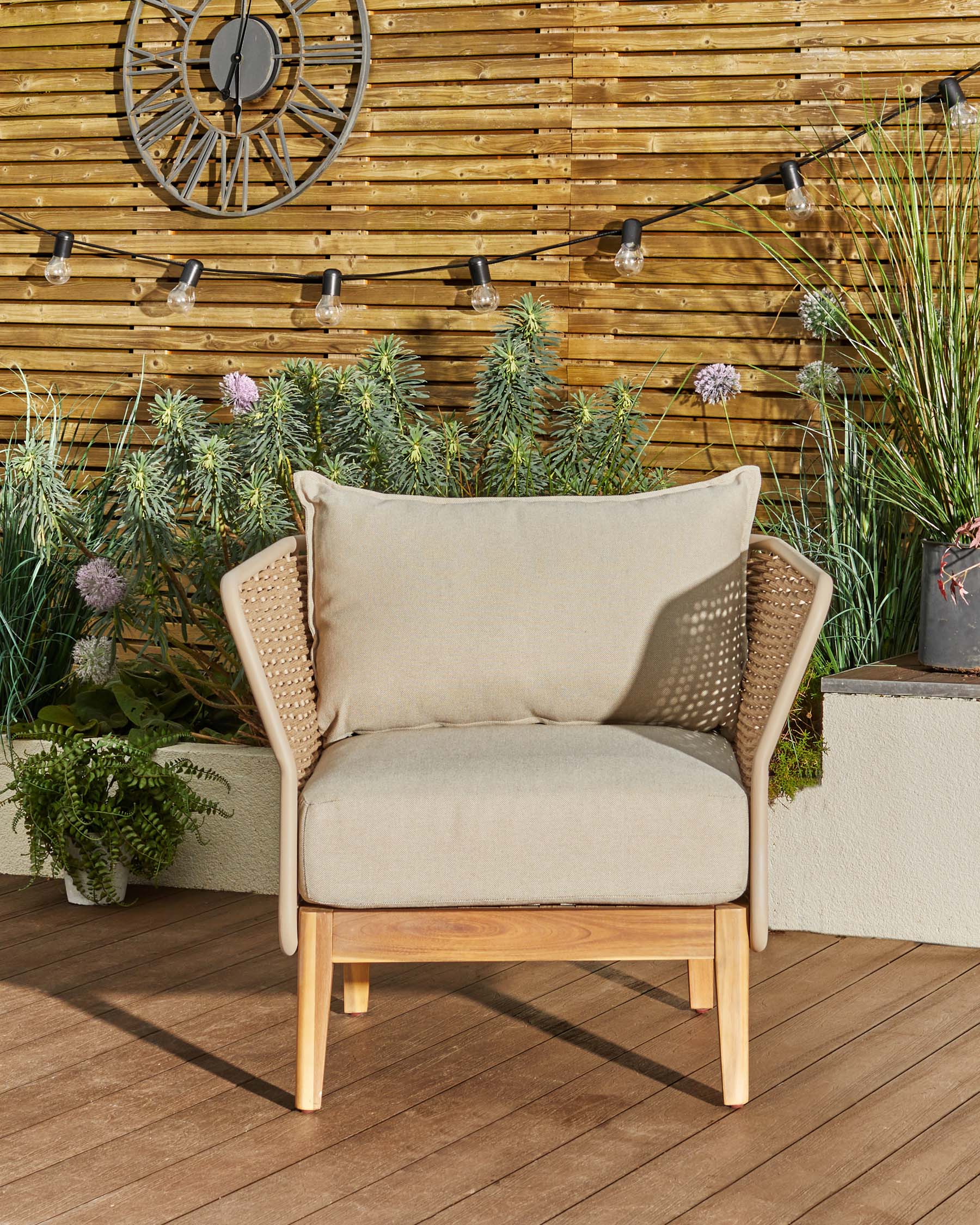 Tuscany garden armchair in natural acacia wood with cream fabric cushions, woven rattan armrests, displayed on wooden deck.