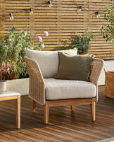 Tuscany garden armchair in natural acacia wood with beige fabric cushions, displayed on a wooden deck with potted plants and string lights.