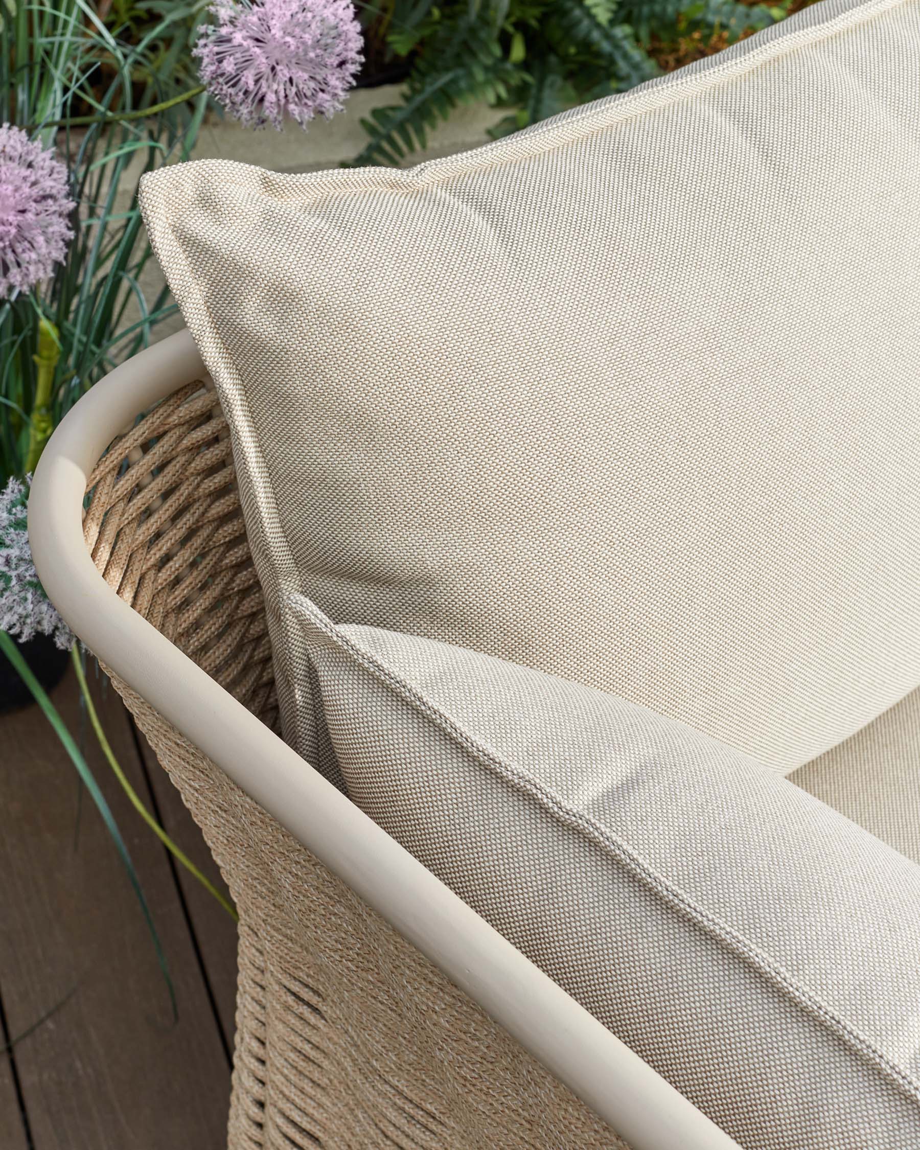 Tuscany garden armchair with natural acacia wood frame and cream fabric seat, angled view showing curved armrest detail.