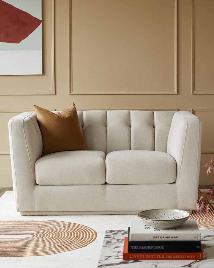 A cream two-seater sofa with a tan cushion. A modern, stylish piece perfect for a small space.