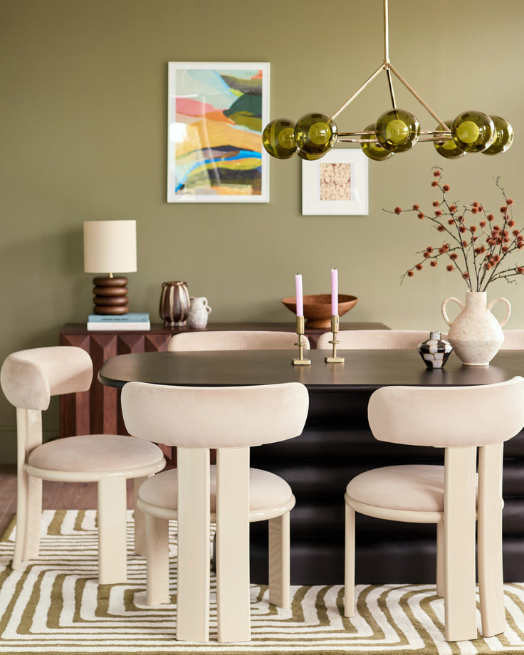 Champagne velvet dining chair with curved backrest and cylindrical legs in a modern dining room setting.
