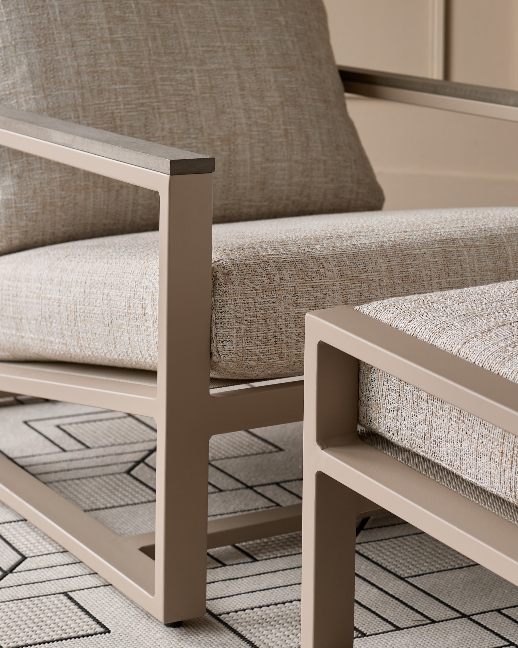 Verano lounge chair with natural wood base and beige upholstered seat and backrest, shown at an angle on patterned rug.