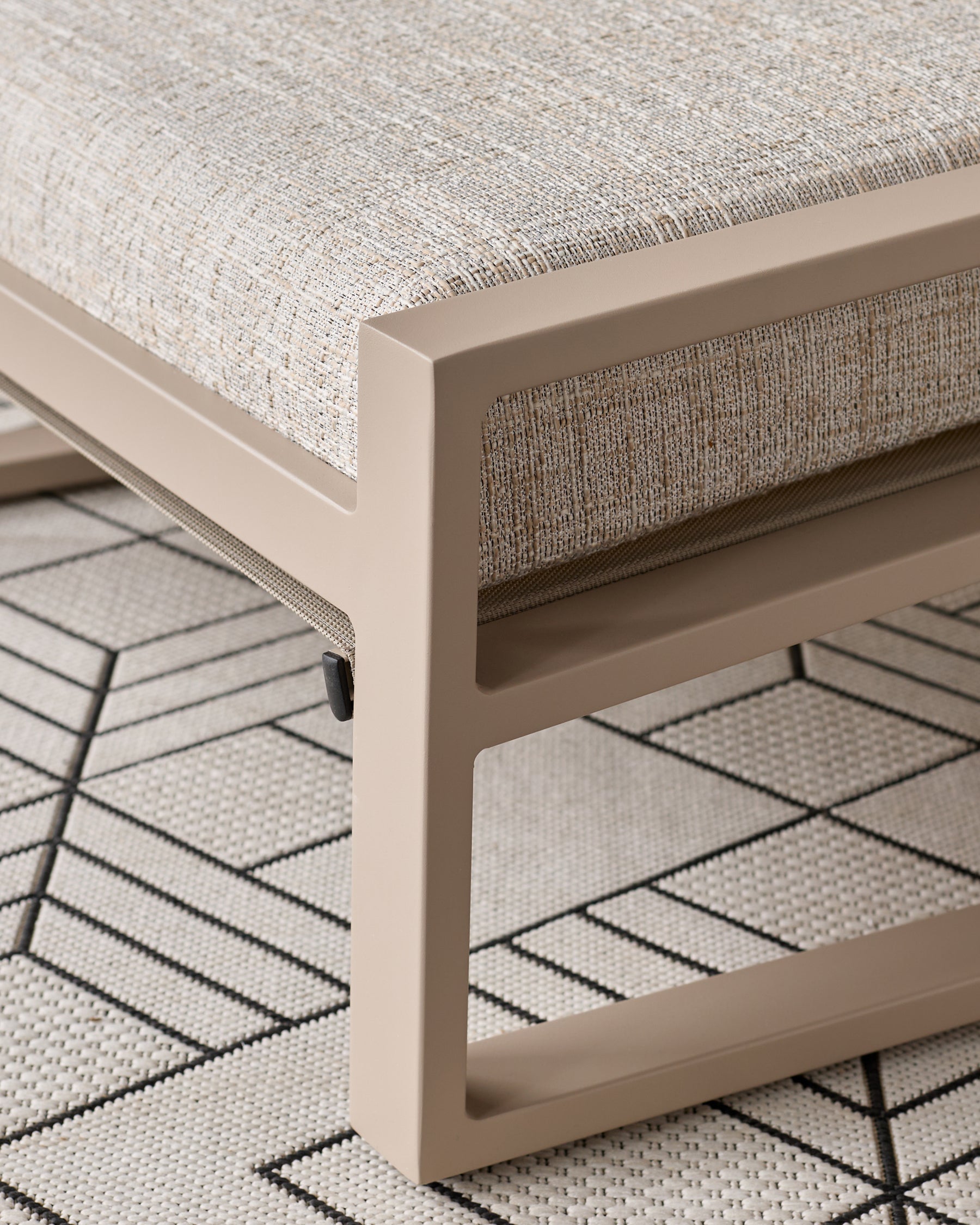 Verano lounge chair with natural wooden base and beige upholstery, close-up of armrest and leg detail on patterned rug.