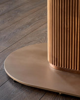 Vidal 6-seater dining table in natural ceramic with round beige top and fluted wood base detail on dark wooden floor.
