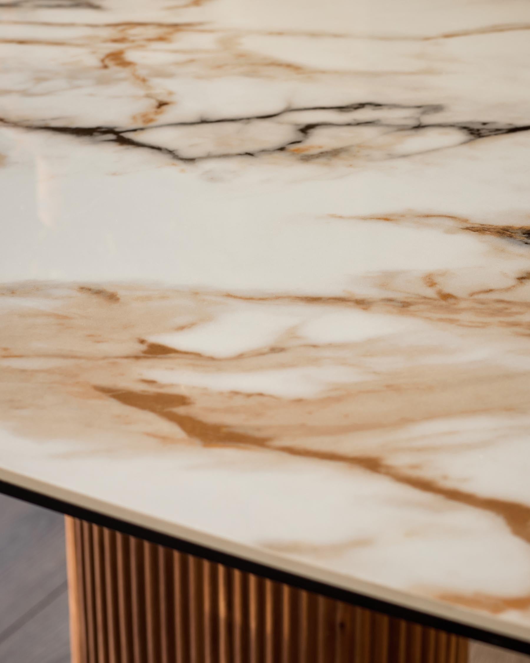 Vidal dining table top detail showing natural ceramic surface with warm beige and brown veining, wood base with ribbed texture visible below.