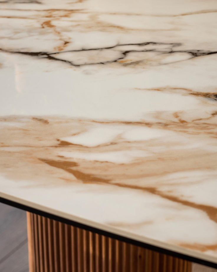 Vidal dining table top detail showing natural ceramic surface with warm beige and brown veining, wood base with ribbed texture visible below.