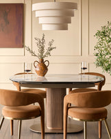 Vidal extending dining table in natural ceramic with glass top, seated with four tan leather chairs in styled dining room.