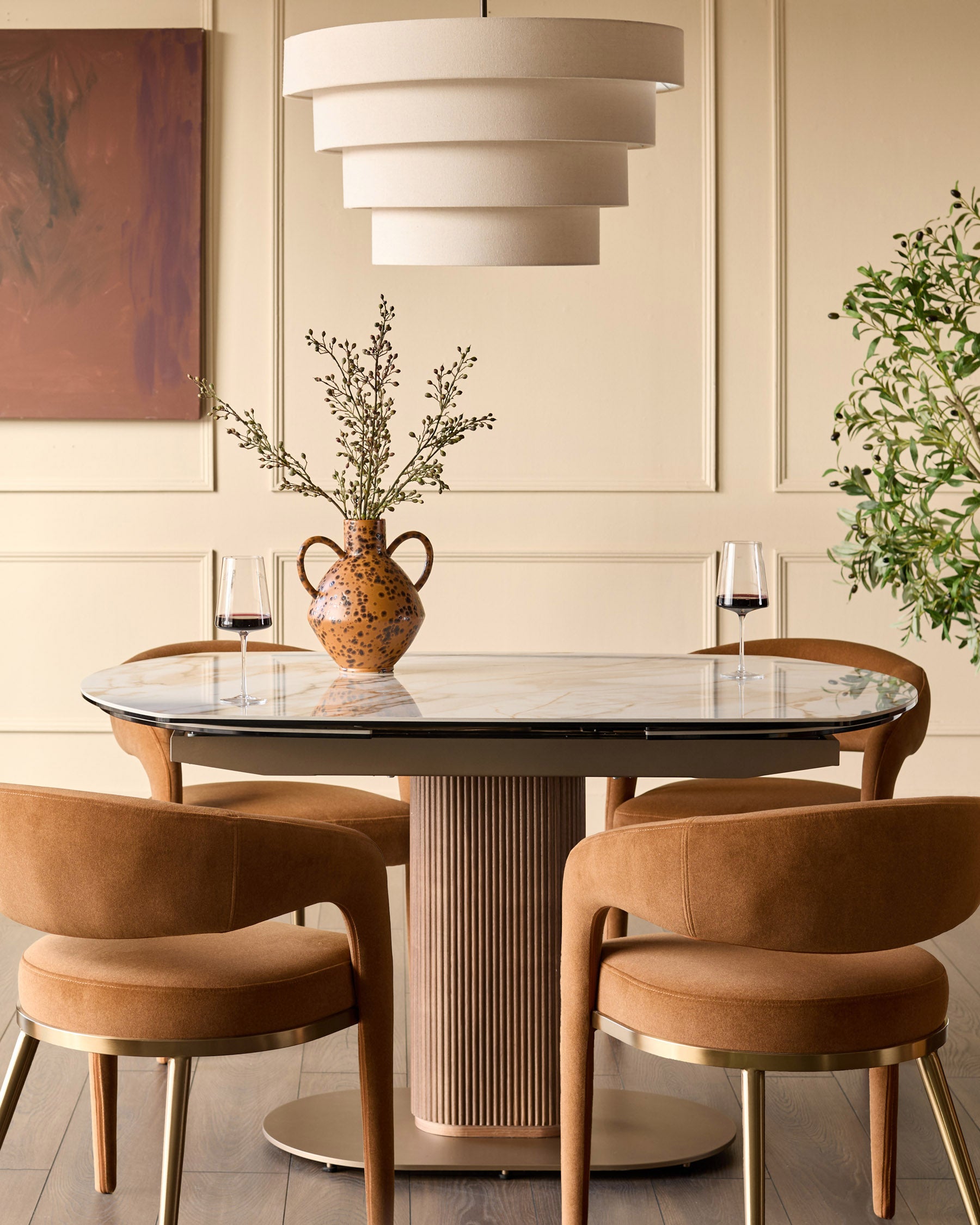 Vidal extending dining table in natural ceramic with glass top, seated with four tan leather chairs in styled dining room.