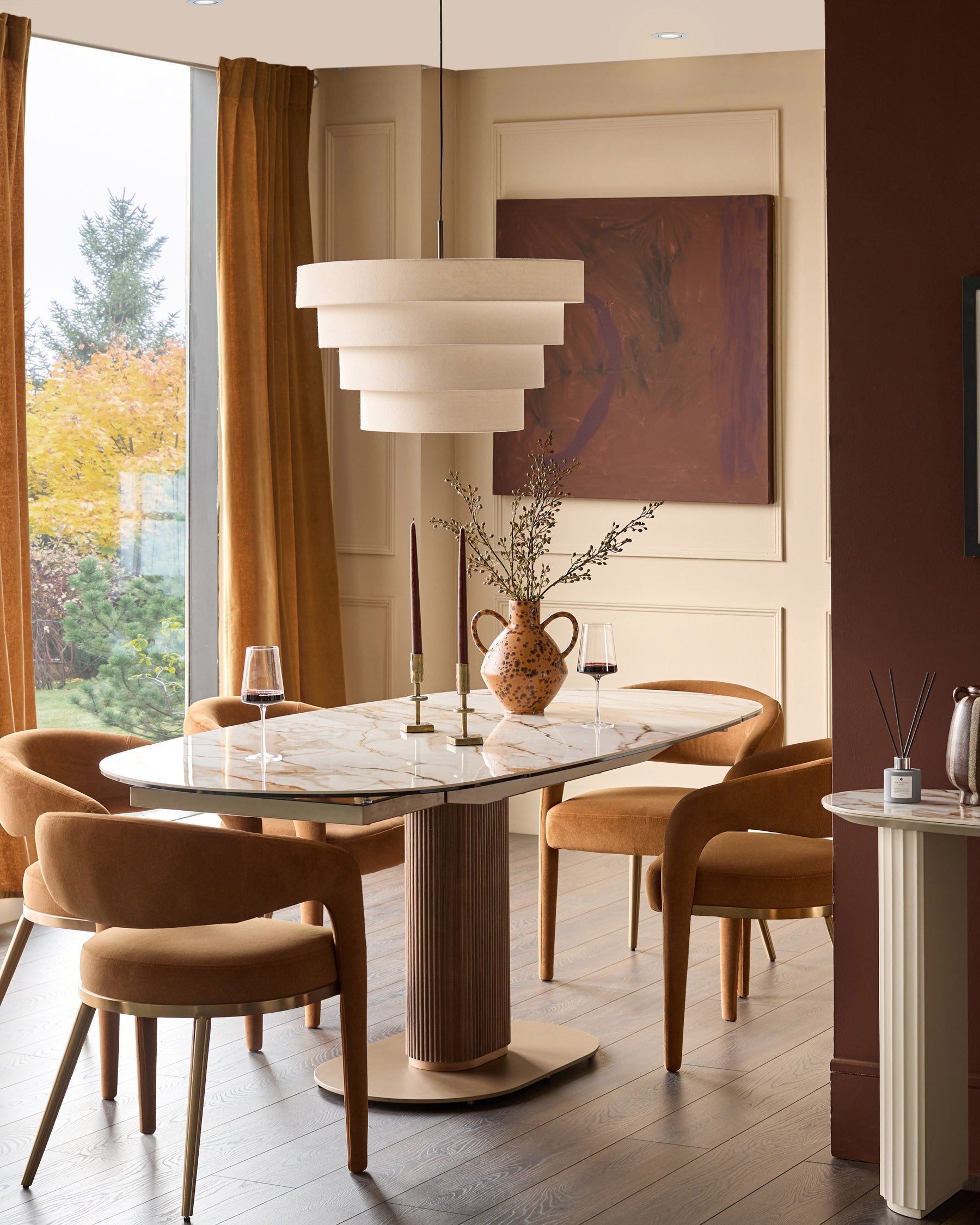 Vidal extending dining table in natural ceramic with marble-effect top, seated by four caramel velvet chairs in warm dining room setting.