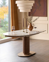 Vidal extending dining table in natural ceramic with walnut base, oval top, styled with candles and floral arrangement.