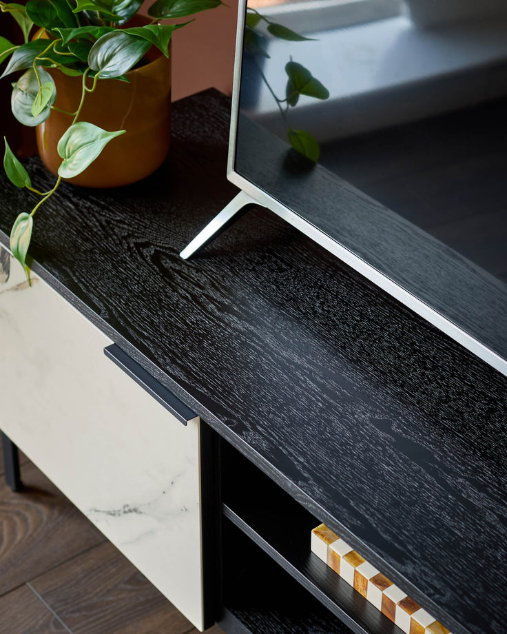 Winslow TV unit in black wood finish with white marble front panel, showing open shelf detail and decorative items.