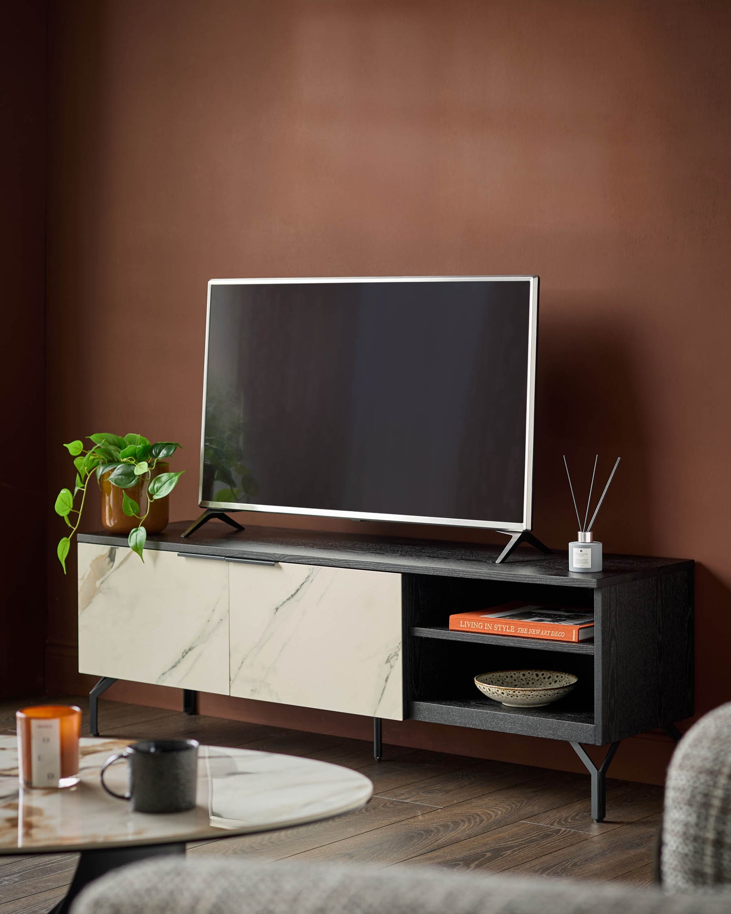 Winslow TV unit with marble-effect ceramic doors, black shelving, and metal legs in a styled living room setting.