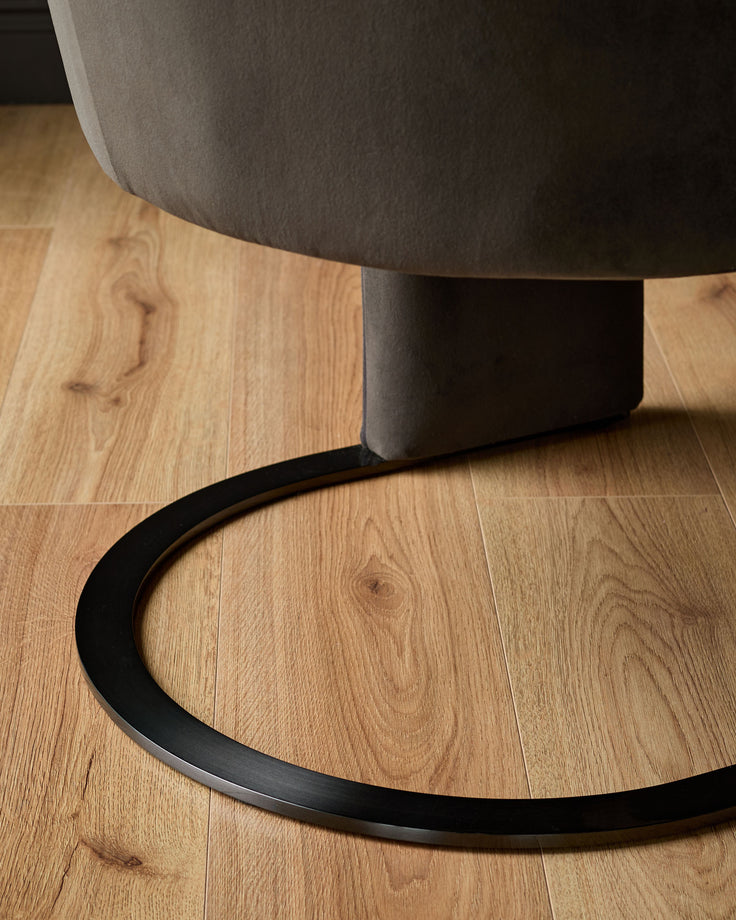 Wren dining chair in grey velvet showing curved black metal base on wooden floor.