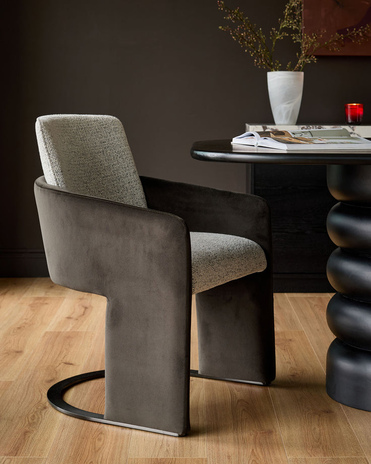 Wren cantilever dining chair in grey velvet and dark chocolate, shown at an angle with black metal base on wooden floor.