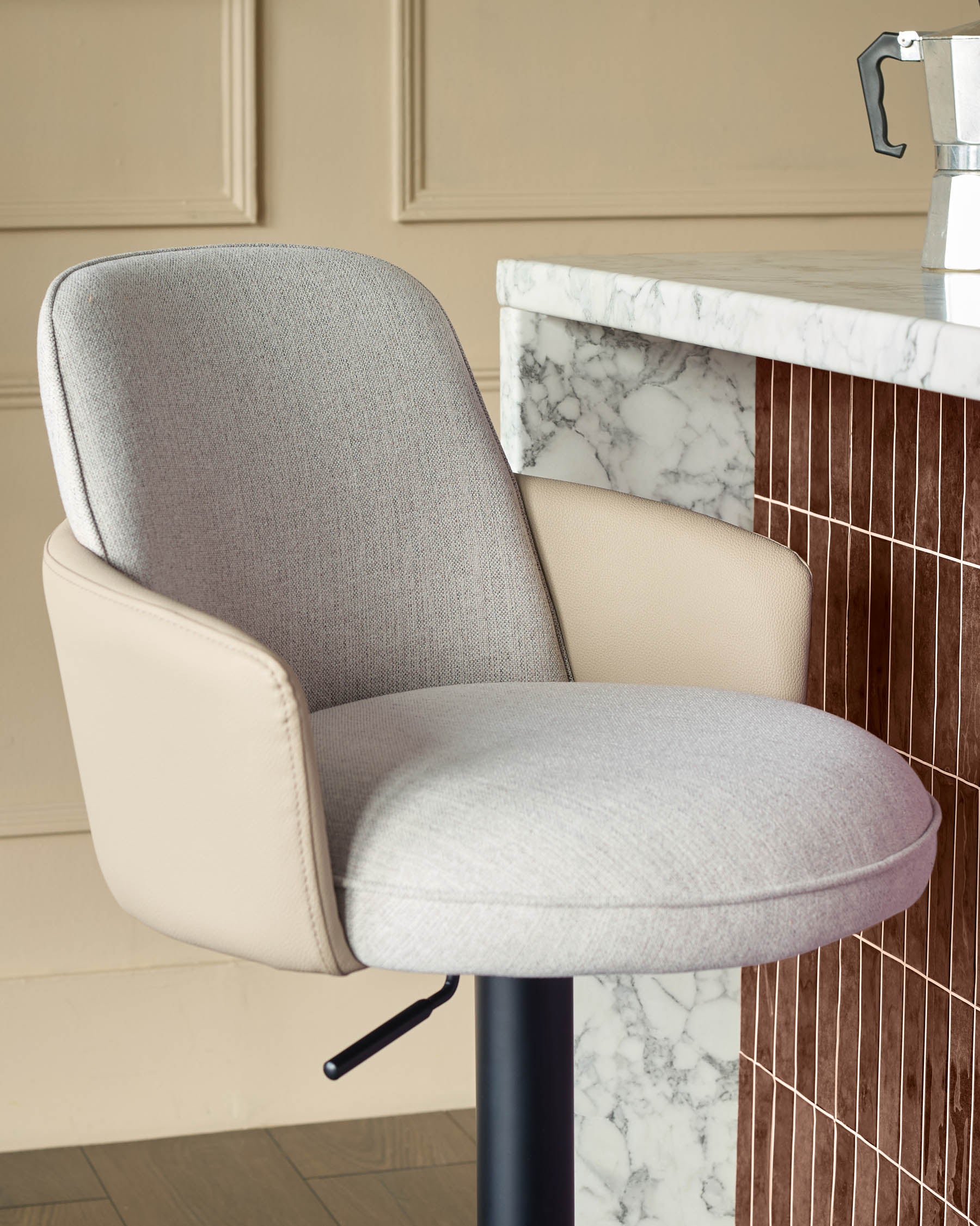 Wren gas lift bar stool in natural fabric and faux leather with rounded backrest, shown at marble counter.