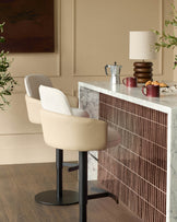 Wren gas lift bar stool in natural faux leather with black metal base, shown at kitchen counter.