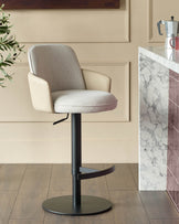 Wren gas lift bar stool in natural fabric with faux leather trim, black base, shown in cream kitchen setting.