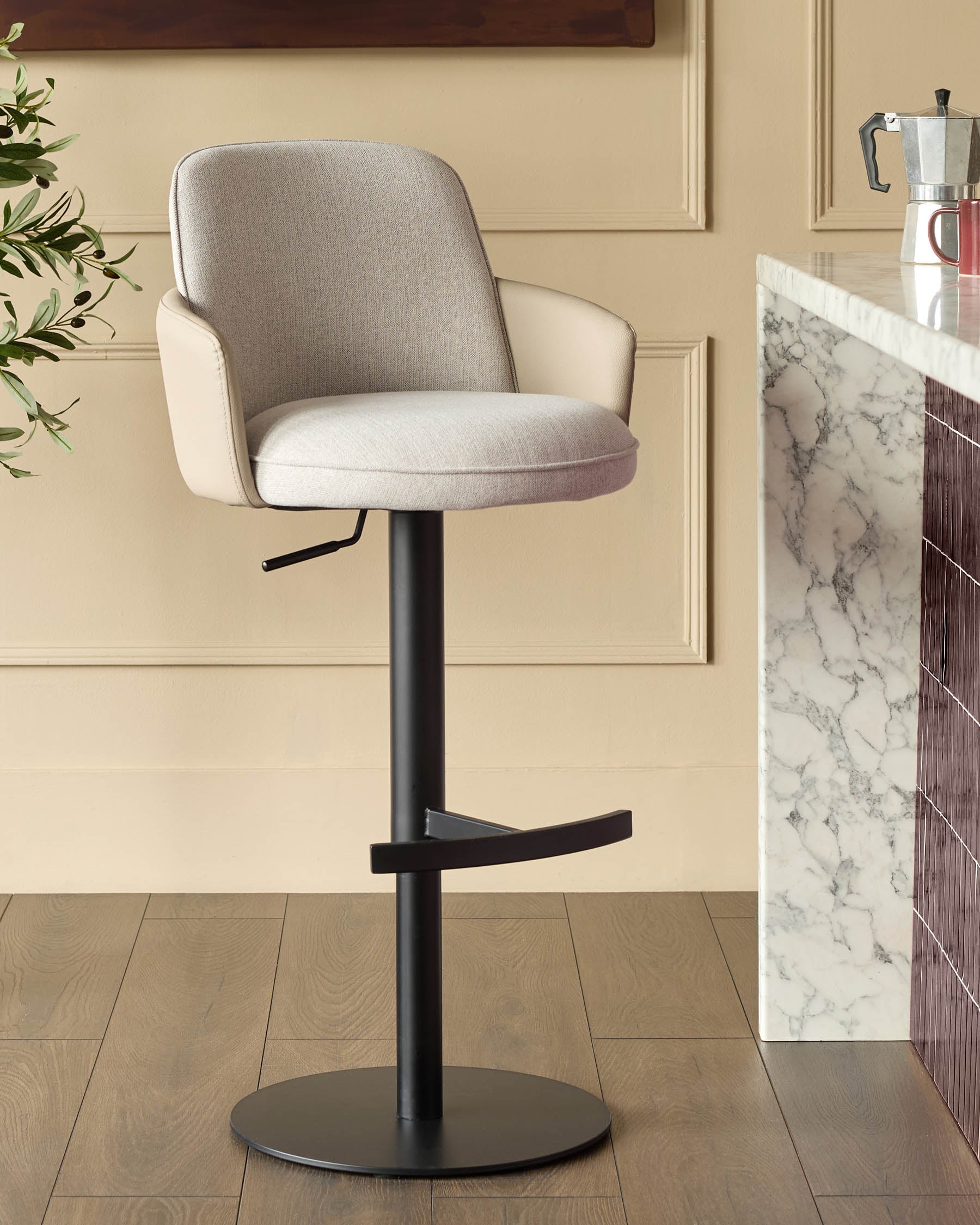 Wren gas lift bar stool in natural fabric with black metal base, shown in kitchen setting next to marble countertop.